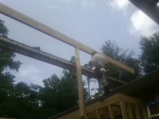 Carpenter setting a ridge beam over a new addition frame — Ice Dam Removal by Roofing Brothers in Leonardo