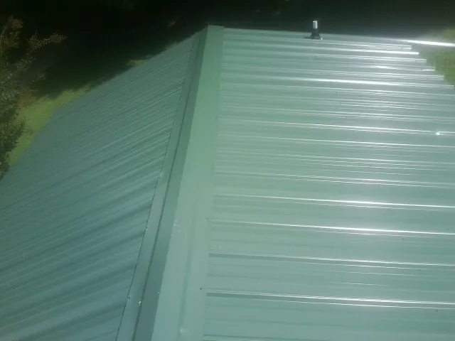 New green metal panels meeting at the ridge of a roof — Flat Roof Repair work by our crew in Leonardo