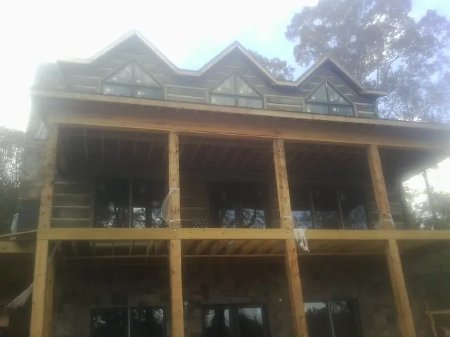 Dormers and porch framing on a large log home under construction — Roof Coating work by our crew in Leonardo