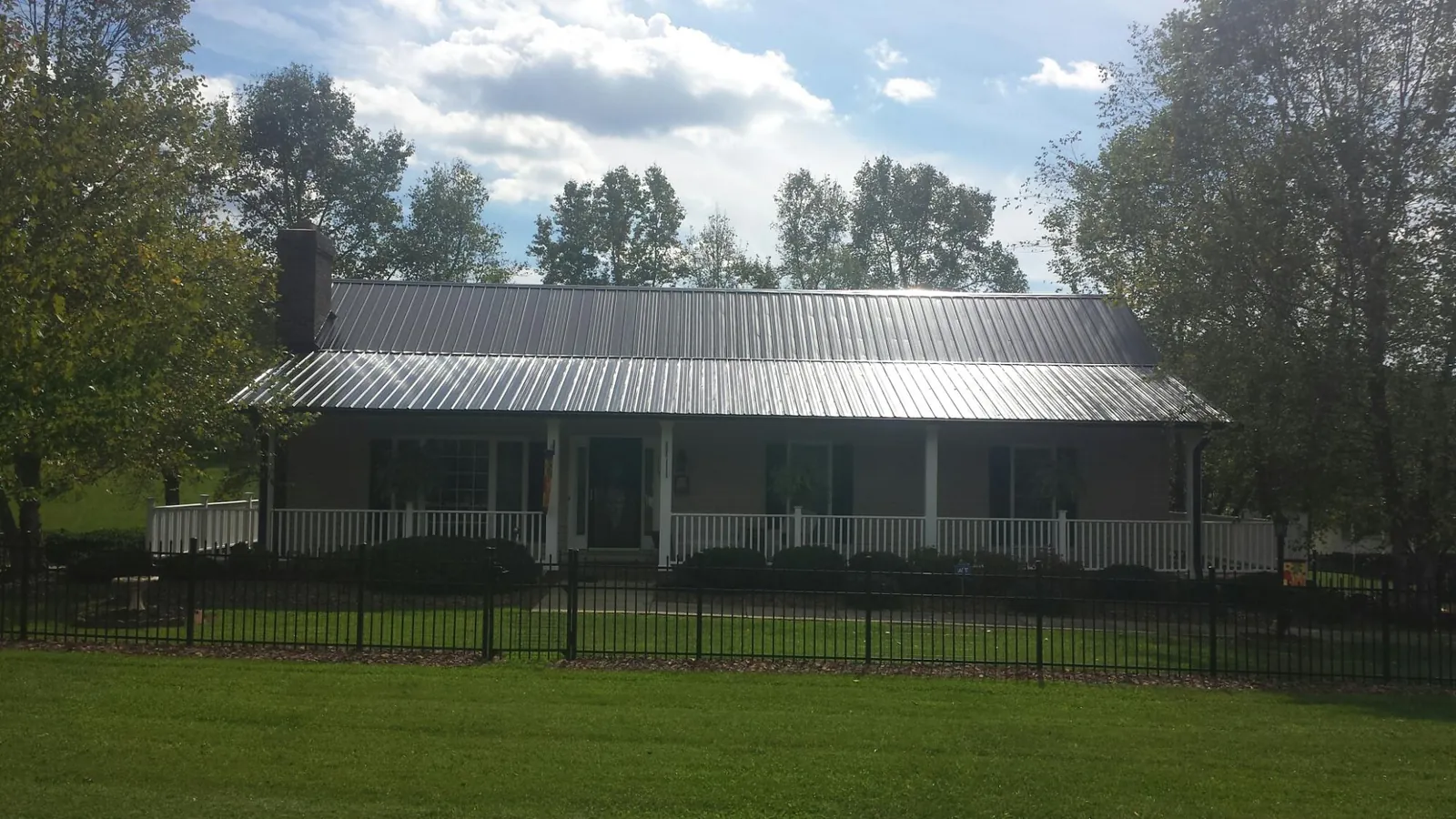 Gray metal roof on a brick ranch with a full width front porch — Gutter Guard Installation work by our crew in Leonardo