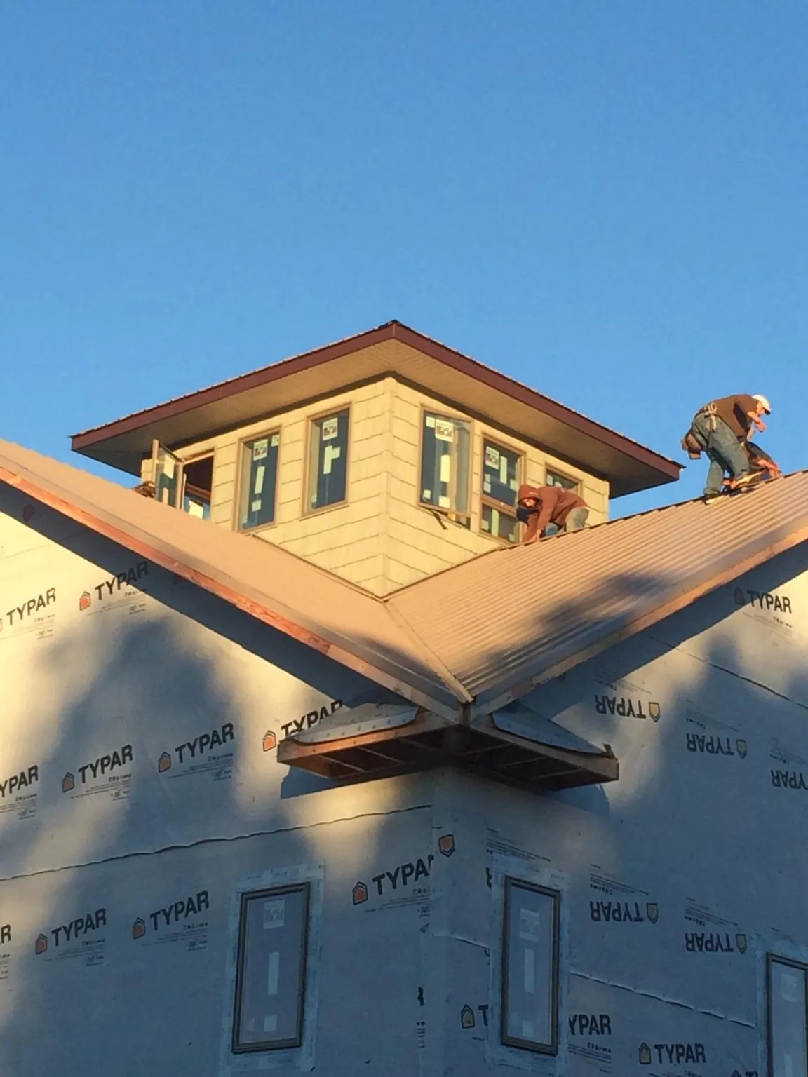 Roofers working around a rooftop cupola on a new metal roof at sunset — Roof Waterproofing in Leonardo by Roofing Brothers